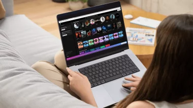 Une jeune femme dans son canapé écoutant Spotify depuis son PC portable